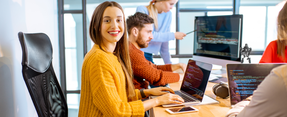 Smiling woman coding on a laptop in the office